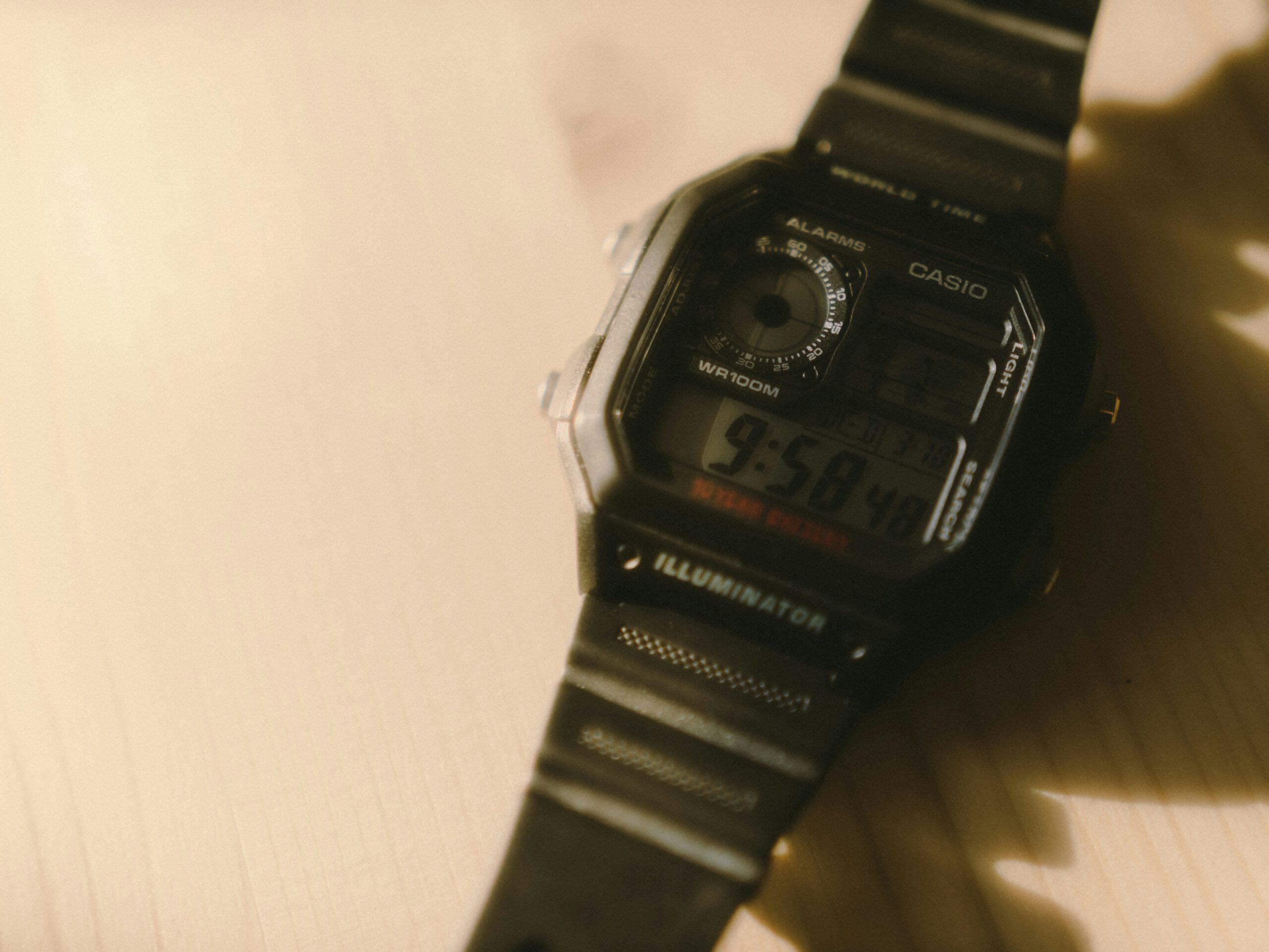 Zwart vierkant digitaal kunststof Casio horloge op houten ondergrond.