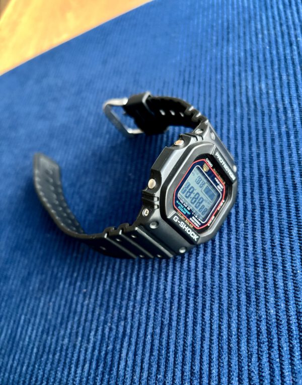 Zwart kunststof digitaal Casio G-Shock horloge op blauwe ondergrond.