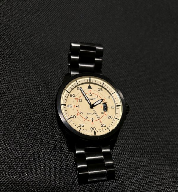 Zwart en beige zandkleur Citizen analoog piloten horloge met datum aanduiding op zwarte ondergrond.