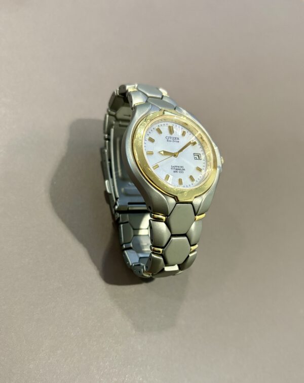 Grijs met goud Citizen horloge van titanium met saffier glas op grijze ondergrond.