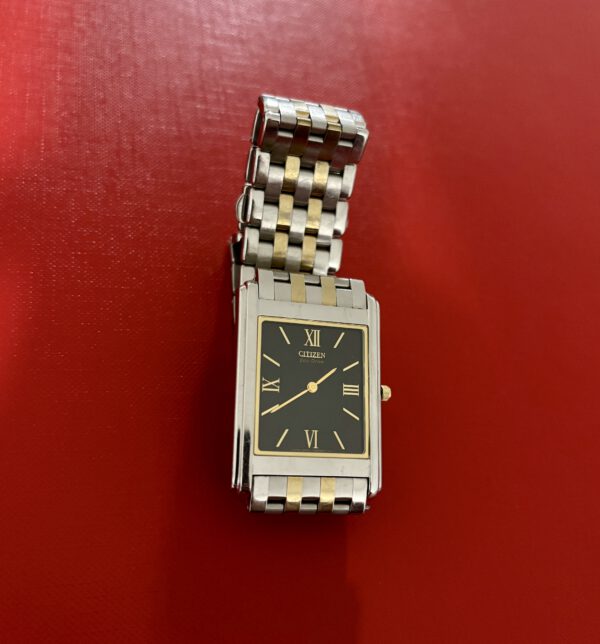 Goud met zilver vierkant klassiek Citizen horloge op rode ondergrond.